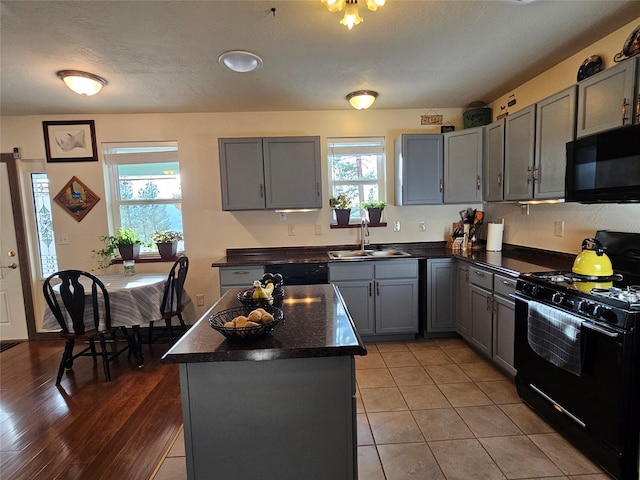 kitchen with a wealth of natural light, sink, a kitchen island, and black appliances