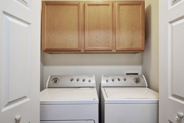 laundry room featuring washing machine and clothes dryer and cabinets