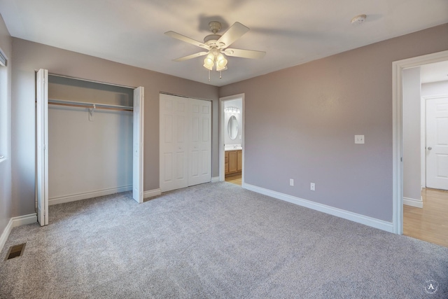 unfurnished bedroom featuring ceiling fan, light carpet, connected bathroom, and two closets