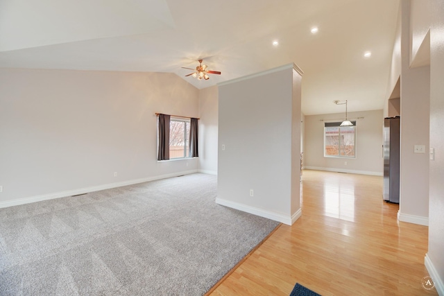 spare room with ceiling fan, light wood-type flooring, lofted ceiling, and a healthy amount of sunlight