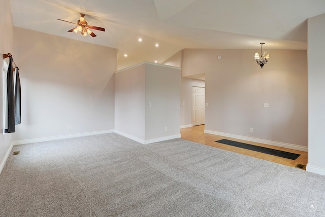 spare room featuring light carpet, lofted ceiling, and ceiling fan with notable chandelier