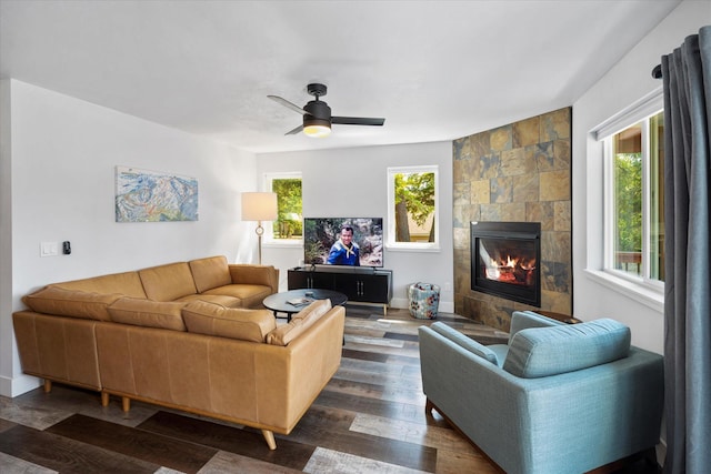 living area featuring a ceiling fan, dark wood-style flooring, and a tile fireplace