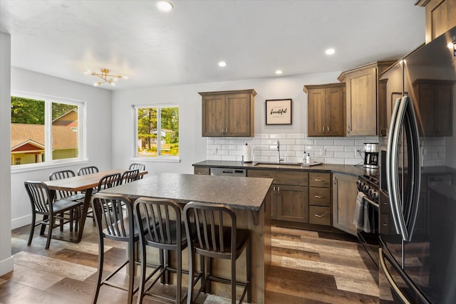 kitchen featuring dark countertops, backsplash, range with gas cooktop, freestanding refrigerator, and a sink