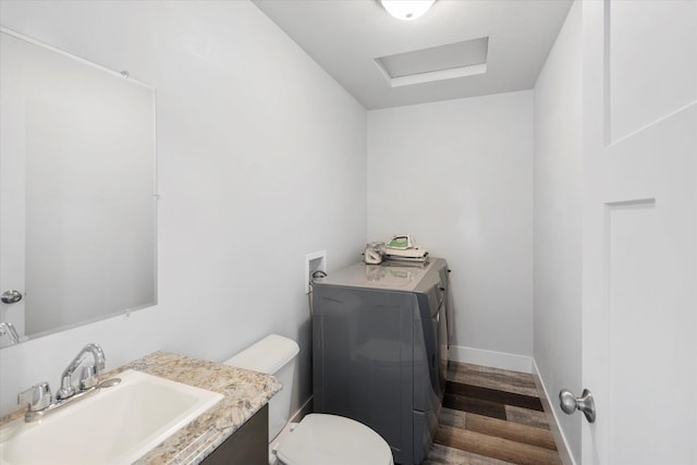 half bath featuring vanity, wood finished floors, baseboards, washer / clothes dryer, and toilet