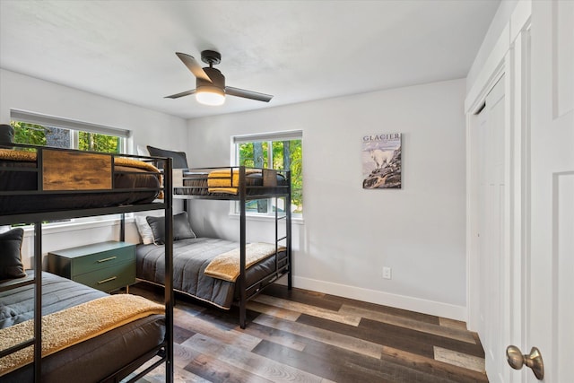 bedroom with dark wood-style floors, ceiling fan, and baseboards