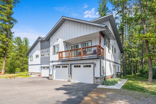 view of front of property featuring a garage, stone siding, board and batten siding, and driveway