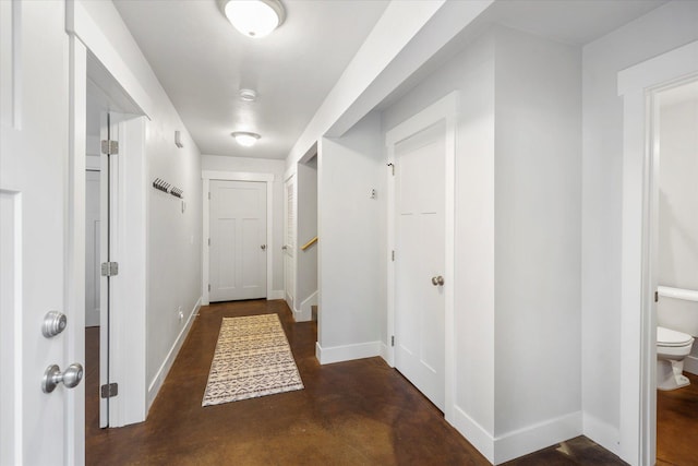 corridor with baseboards and finished concrete floors