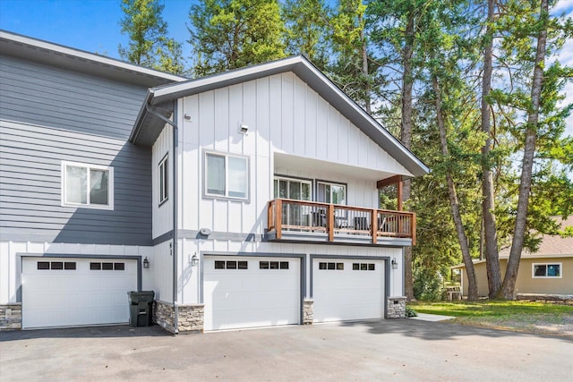 view of front of property featuring a garage, stone siding, and driveway