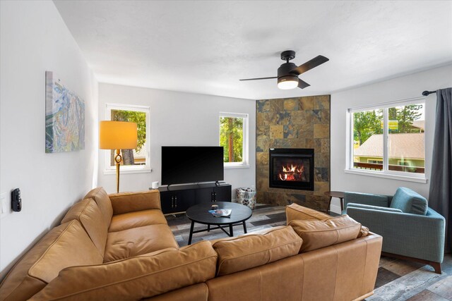 living area featuring a wealth of natural light, a ceiling fan, wood finished floors, and a tiled fireplace