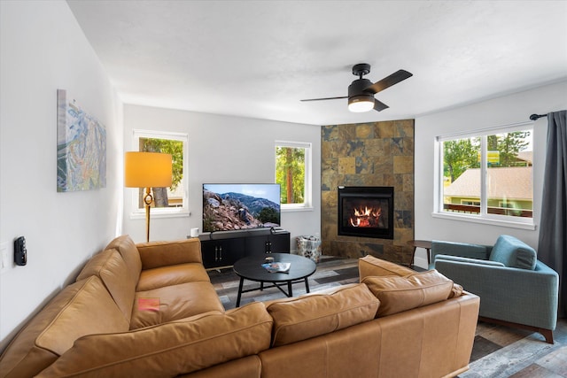 living area featuring ceiling fan, plenty of natural light, wood finished floors, and a tile fireplace