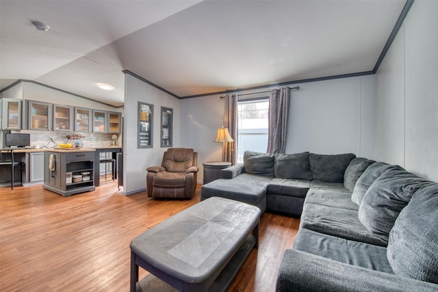 living room with wood-type flooring, crown molding, and lofted ceiling