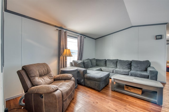 living room featuring light hardwood / wood-style flooring, crown molding, and vaulted ceiling