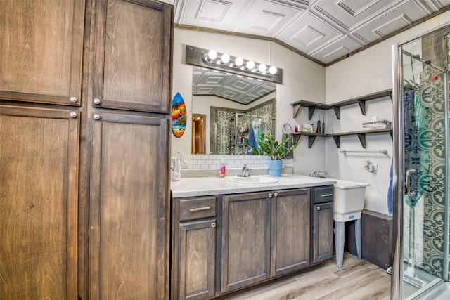 bathroom with vanity, vaulted ceiling, decorative backsplash, hardwood / wood-style flooring, and an enclosed shower