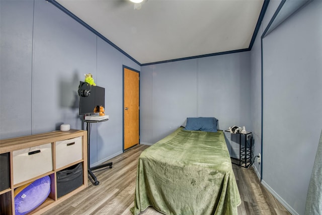 bedroom with vaulted ceiling, ornamental molding, and hardwood / wood-style floors