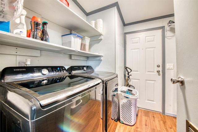 clothes washing area featuring washing machine and dryer, ornamental molding, and light hardwood / wood-style flooring