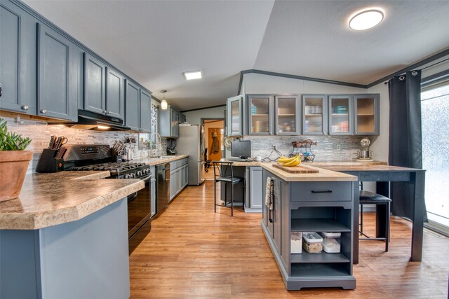 kitchen with gray cabinetry, vaulted ceiling, sink, hanging light fixtures, and a breakfast bar area