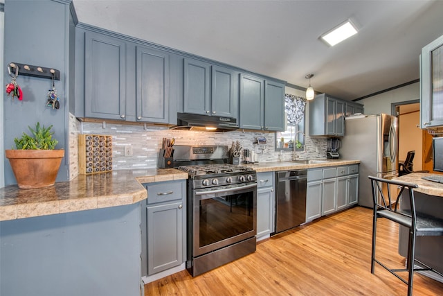 kitchen featuring appliances with stainless steel finishes, sink, backsplash, ornamental molding, and light wood-type flooring