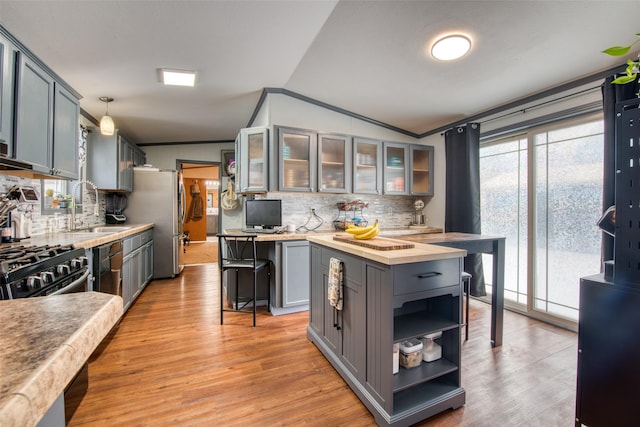 kitchen featuring lofted ceiling, a kitchen bar, sink, hanging light fixtures, and gray cabinetry