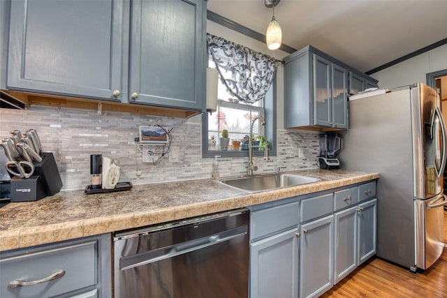 kitchen featuring light hardwood / wood-style floors, stainless steel appliances, hanging light fixtures, ornamental molding, and sink