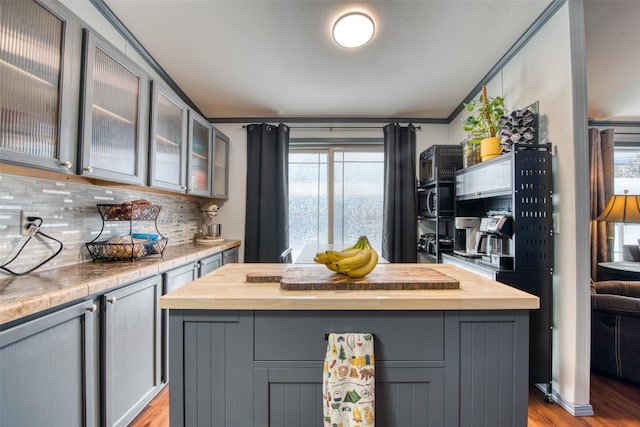 kitchen with wooden counters, gray cabinets, backsplash, light wood-type flooring, and a center island