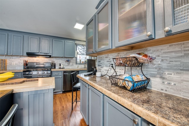 kitchen featuring black gas range oven, stainless steel dishwasher, backsplash, and light hardwood / wood-style floors