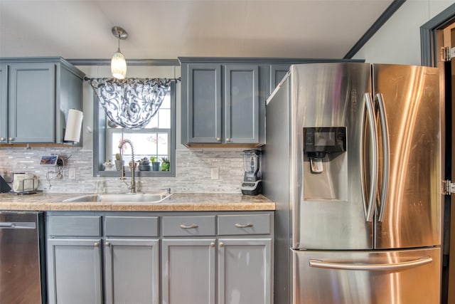 kitchen with pendant lighting, decorative backsplash, sink, crown molding, and stainless steel appliances