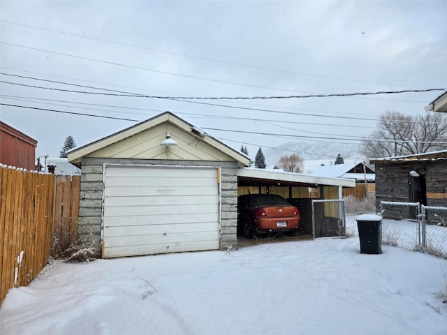 snow covered garage with a carport