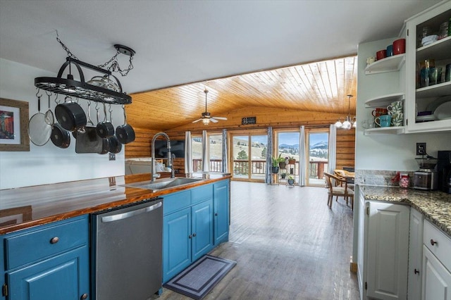 kitchen with dishwasher, blue cabinets, rustic walls, and lofted ceiling