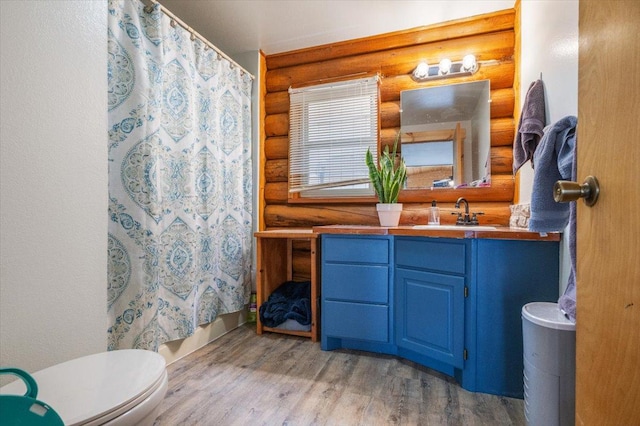 full bathroom featuring vanity, toilet, log walls, and hardwood / wood-style flooring