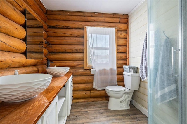 bathroom featuring log walls, vanity, and hardwood / wood-style flooring