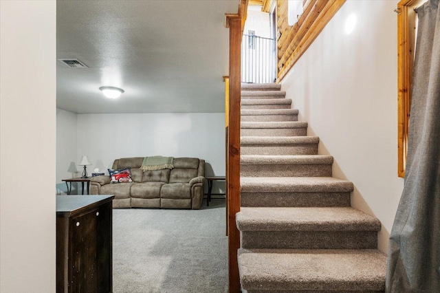 stairs with a textured ceiling and carpet floors