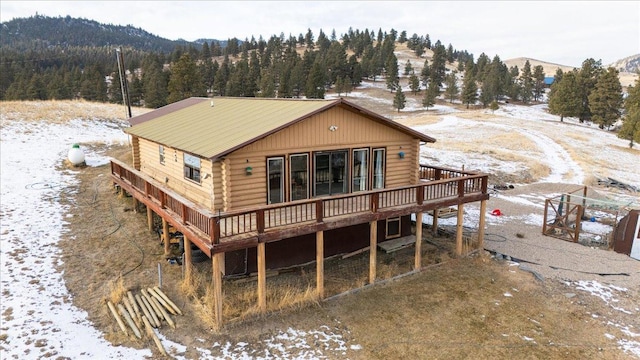 snow covered rear of property with a deck with mountain view