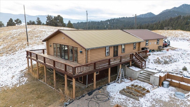 snow covered back of property with a deck with mountain view