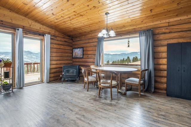 dining area with vaulted ceiling, a notable chandelier, a mountain view, hardwood / wood-style floors, and a wood stove