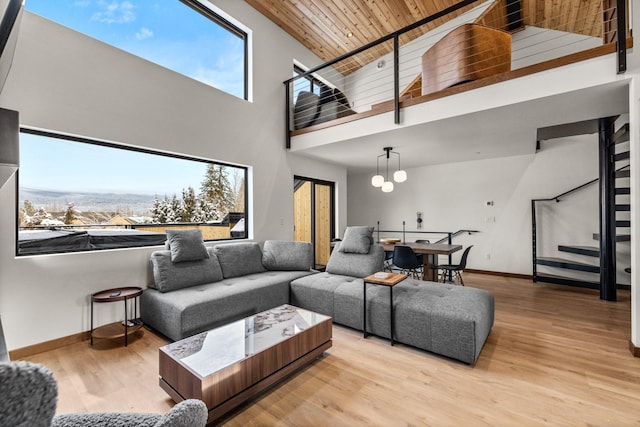 living room with a high ceiling, light wood-type flooring, a notable chandelier, and wood ceiling