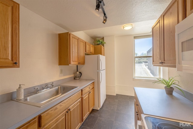 kitchen with sink, track lighting, a textured ceiling, and white appliances