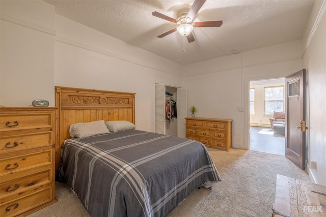 bedroom featuring a textured ceiling, light colored carpet, a closet, and ceiling fan