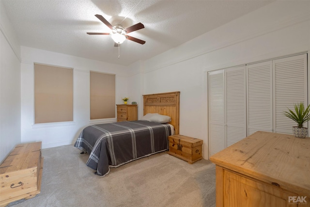 bedroom featuring light carpet, a textured ceiling, a closet, and ceiling fan