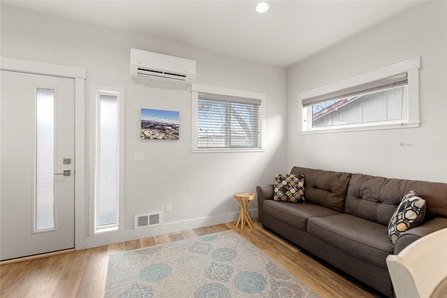 living room with a wall unit AC and light wood-type flooring