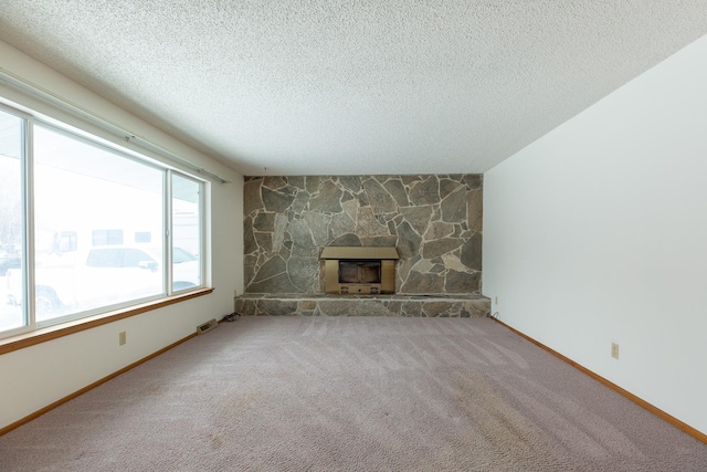 unfurnished living room featuring a stone fireplace, carpet floors, and a textured ceiling