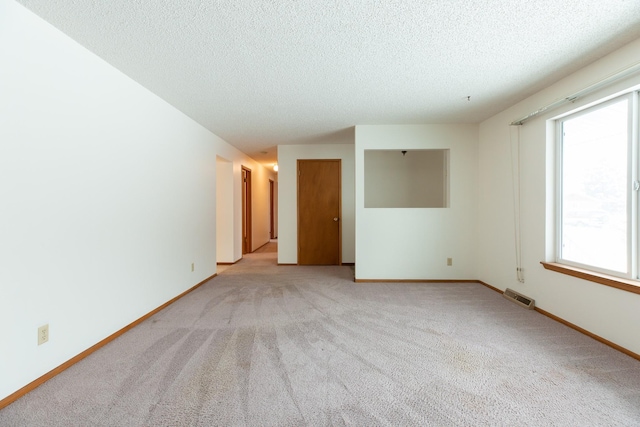 carpeted empty room with a textured ceiling