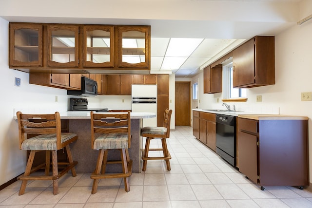 kitchen featuring kitchen peninsula, sink, a breakfast bar area, and black appliances