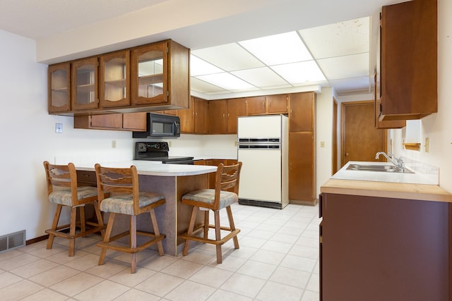 kitchen featuring black appliances, a kitchen bar, kitchen peninsula, and sink