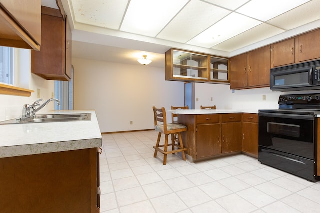 kitchen featuring black appliances, a kitchen bar, kitchen peninsula, and sink