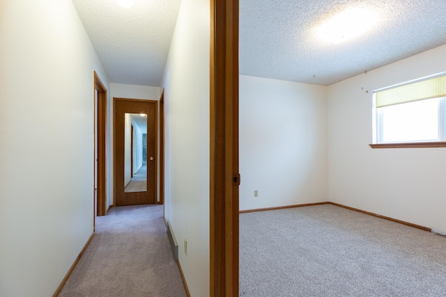 hall featuring a textured ceiling and light carpet