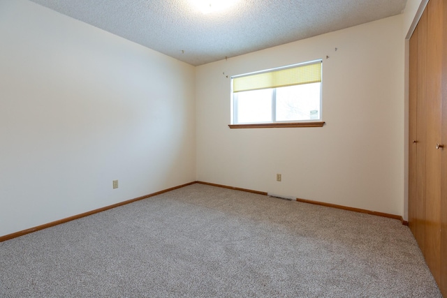 carpeted spare room featuring a textured ceiling