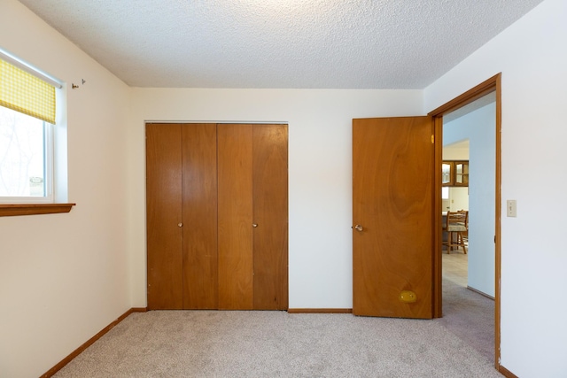 unfurnished bedroom with a closet, light colored carpet, and a textured ceiling