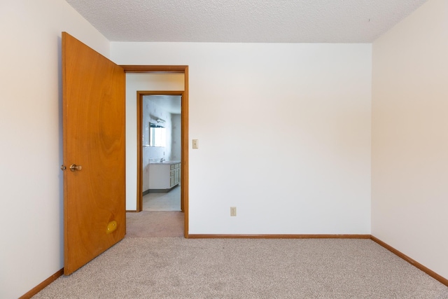 empty room with a textured ceiling and light carpet