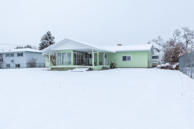 snow covered house featuring a sunroom