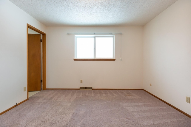 empty room featuring light carpet and a textured ceiling